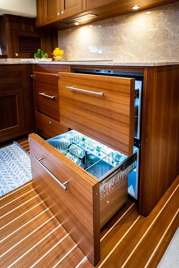 Slide: The Image of The 2020 Ocean 63 Flybridge galley features elegant wood cabinetry and an open refrigerator drawer. - 45