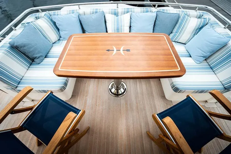 Slide: The Image of The 2020 Hunt Yachts Ocean 63 Flybridge features an elegant seating area with striped cushions and a wooden table. - 19