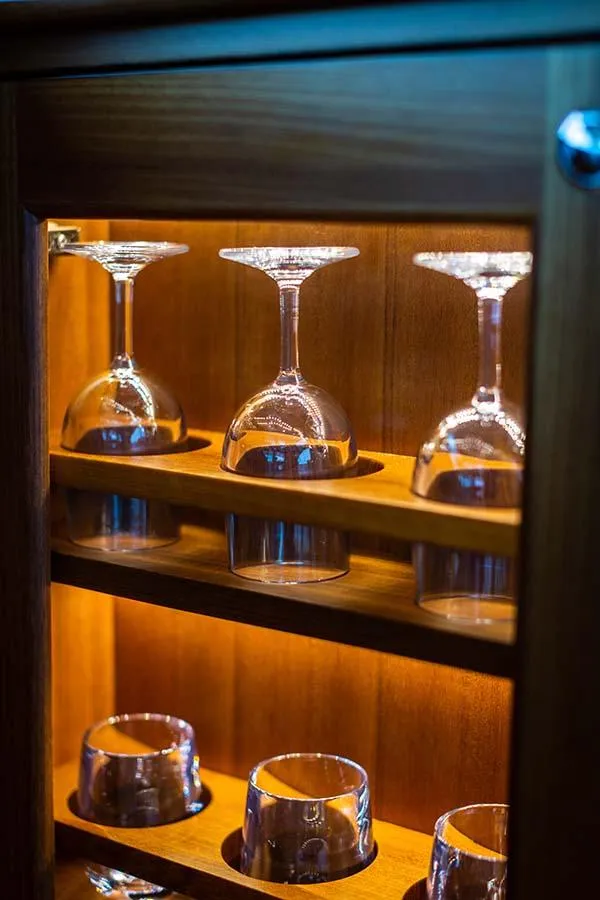 Slide: The Image of A lit cabinet with upside-down wine glasses and whiskey glasses. - 29
