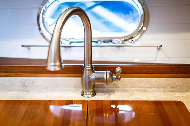 Slide: The Image of A sleek faucet in a yacht kitchen with a wooden countertop and porthole in the background. - 46