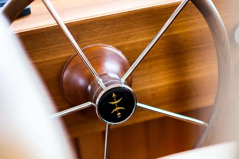 Slide: The Image of The image shows an elegant wooden steering wheel with metal spokes on a yacht. - 34