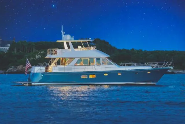 Slide: The Image of 2020 Hunt Yachts Ocean 63 Flybridge on the water at night, with illuminated interior. - 1