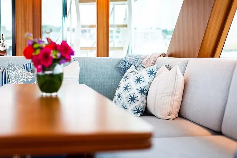 Slide: The Image of A stylish interior with a wooden table, gray sofas, and colorful cushions on a yacht. - 24