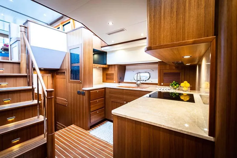 Slide: The Image of The 2020 Hunt Yachts Ocean 63 Flybridge kitchen features elegant wood paneling and modern appliances. - 44