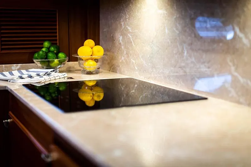Slide: The Image of The 2020 Hunt Yachts Ocean 63 Flybridge kitchen features an elegant countertop with a modern cooktop and decorative lemons and limes. - 47