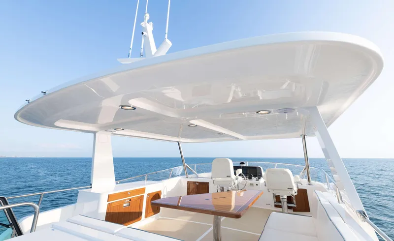 Slide: The Image of Flybridge of the 2020 Hunt Yachts Ocean 63 with table and seating area, surrounded by blue sea. - 6