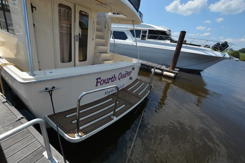 Slide: The Image of 2005 Mainship 34 Trawler docked, featuring "Fourth Quarter" name, sunny day, calm waters. - 15