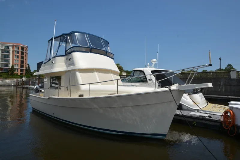 The Image of 2005 Mainship 34 Trawler docked at marina, featuring blue canopy and sleek design. - 1