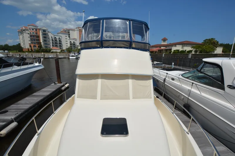 Slide: The Image of 2005 Mainship 34 Trawler docked at marina, surrounded by other boats and buildings. - 4