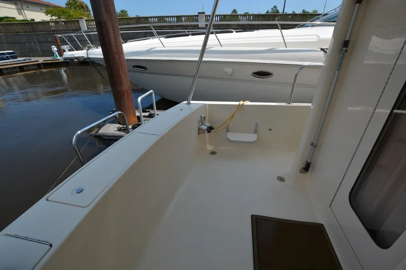 Slide: The Image of 2005 Mainship 34 Trawler docked, showcasing spacious deck and marina surroundings. - 14