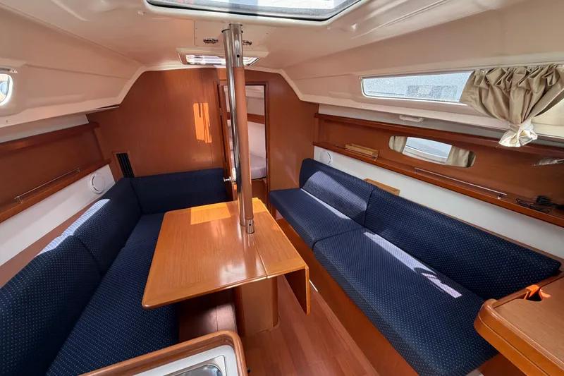 Slide: The Image of Interior of 2009 Beneteau Oceanis 31 sailboat with wooden furnishings and blue seating. - 23