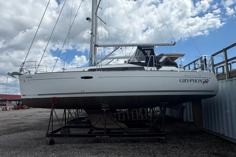 Slide: The Image of 2009 Beneteau Oceanis 31 sailboat on dry dock under cloudy sky. - 0