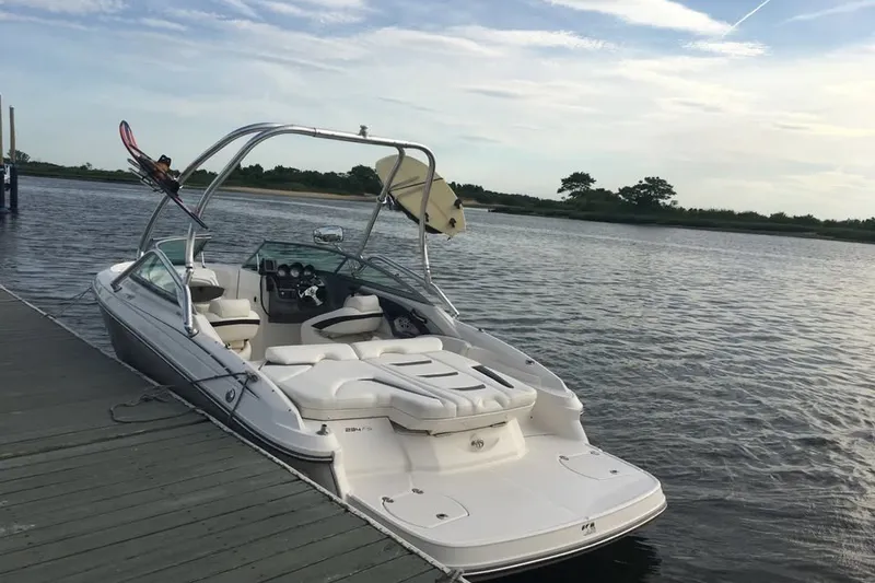 The Image of 2009 Monterey 234FS boat docked on calm water with wakeboard and surfboard. - 0