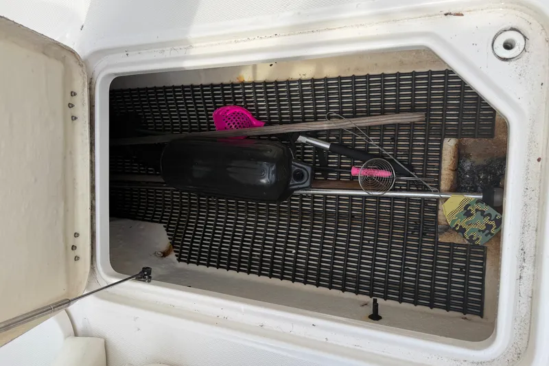 Slide: The Image of An open storage compartment on a boat with a fender, a net, and a paddle. - 18