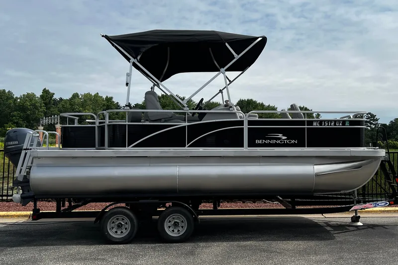 Slide: The Image of 2023 Bennington 20 SF pontoon boat with canopy on trailer, parked outdoors. - 9