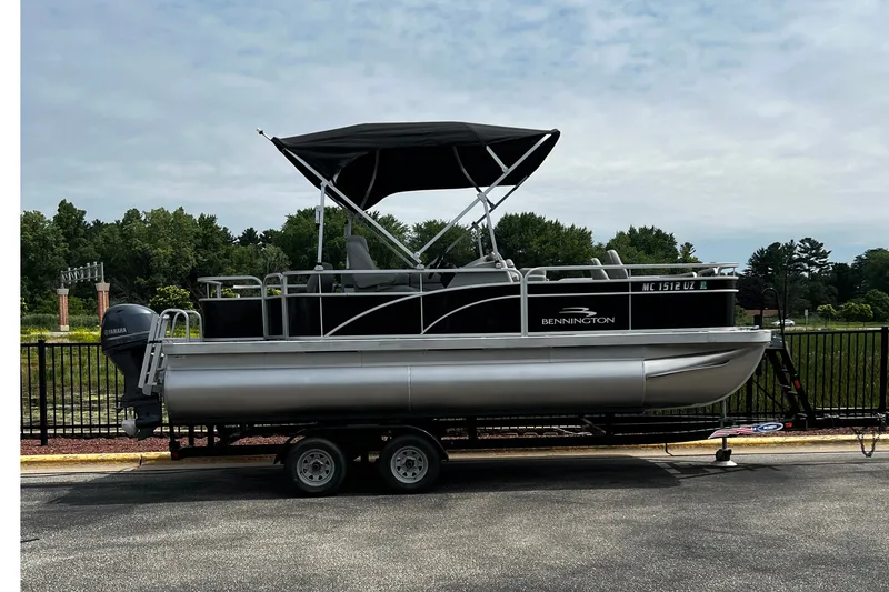 The Image of 2023 Bennington 20 SF pontoon boat on trailer, featuring Yamaha outboard motor. - 0