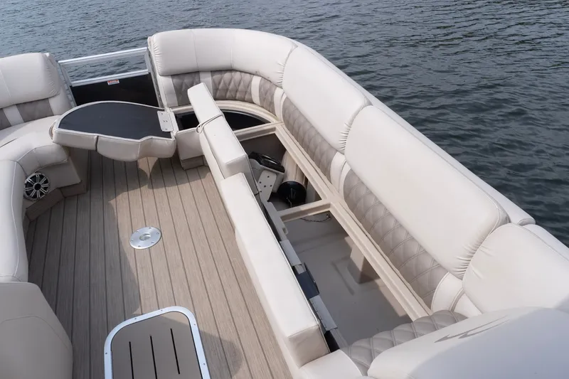 Slide: The Image of 2017 Bennington R25 pontoon boat interior with plush seating and table on water. - 14
