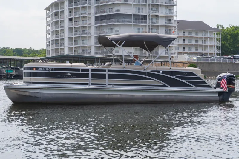 Slide: The Image of 2017 Bennington R25 pontoon boat on water near modern apartment buildings. - 1