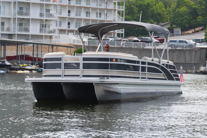 Slide: The Image of 2017 Bennington R25 pontoon boat cruising on a lake near a marina. - 3
