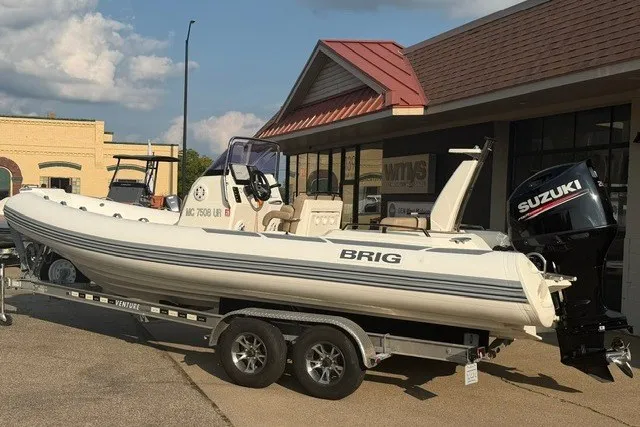Slide: The Image of 2020 Brig Eagle 6.7 boat on trailer with Suzuki outboard motor, parked outside a building. - 12