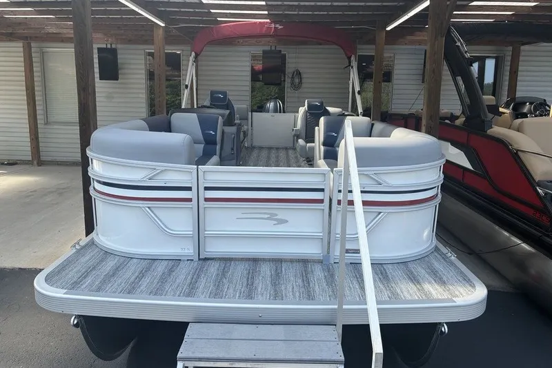 Slide: The Image of 2027 Bennington 22 SSR pontoon boat with spacious seating, docked under a wooden canopy. - 1