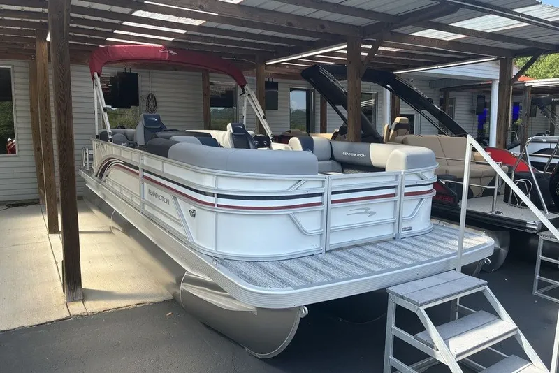 The Image of 2027 Bennington 22 SSR pontoon boat with red canopy, parked under a wooden shelter. - 0