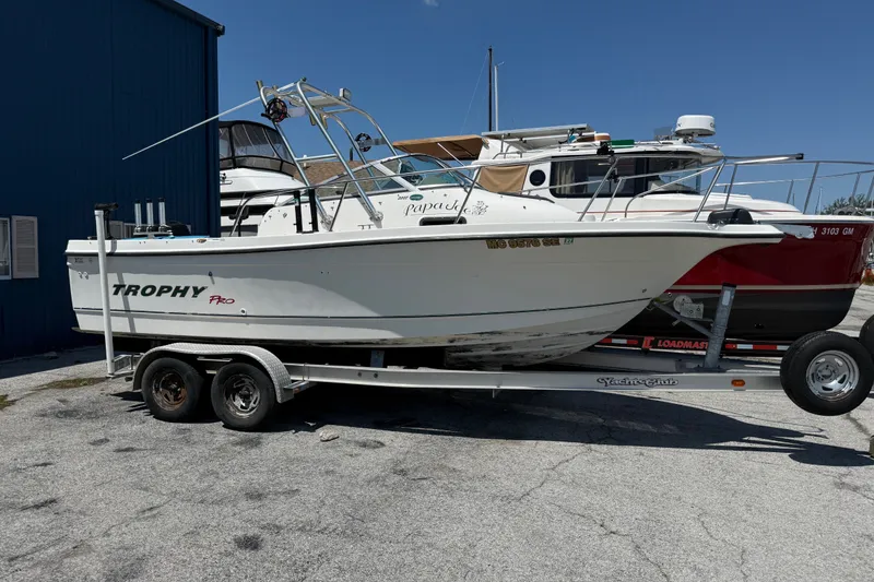 The Image of 2002 Bayliner Trophy Walkaround boat on trailer, parked outdoors under clear blue sky. - 0
