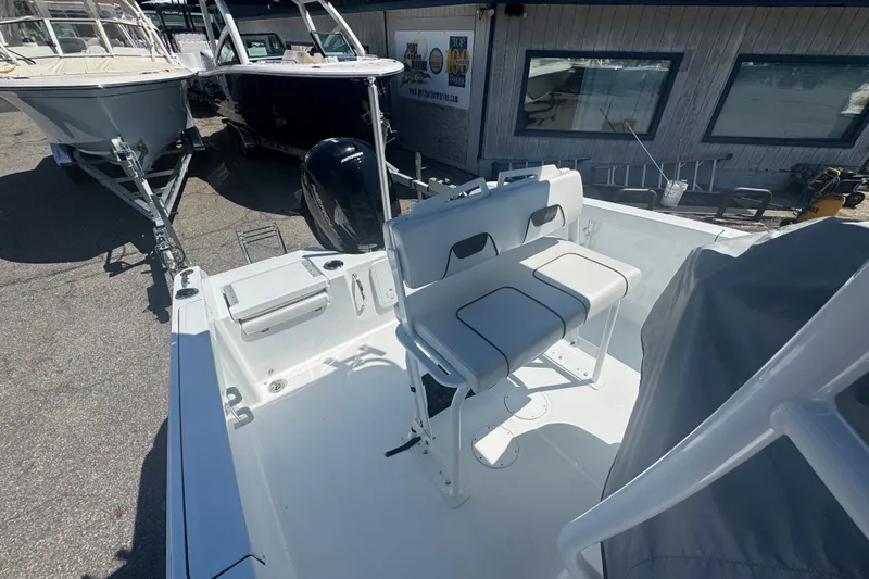 Slide: The Image of 2023 Wellcraft 202 Fisherman boat interior with seating and motor, displayed outdoors. - 11