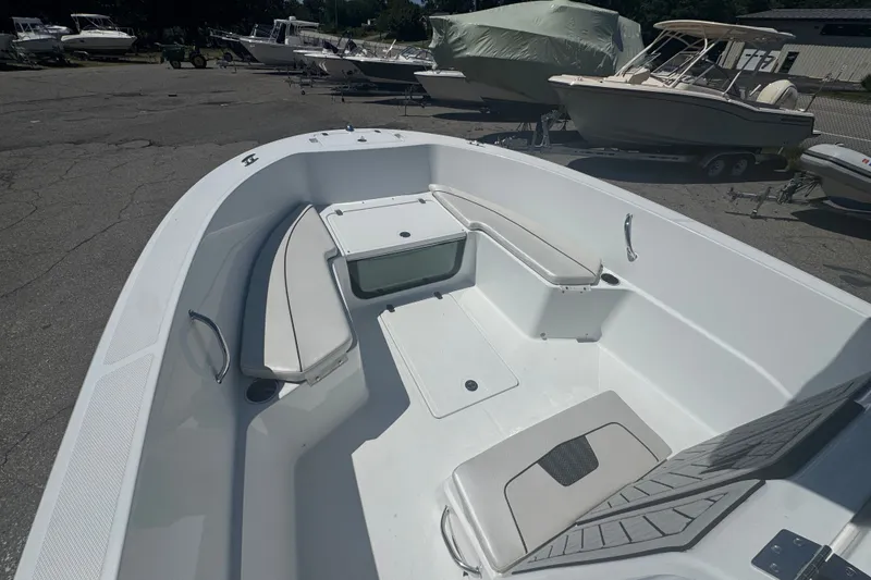 Slide: The Image of 2023 Wellcraft 202 Fisherman boat interior with seating and storage, parked among other boats. - 12