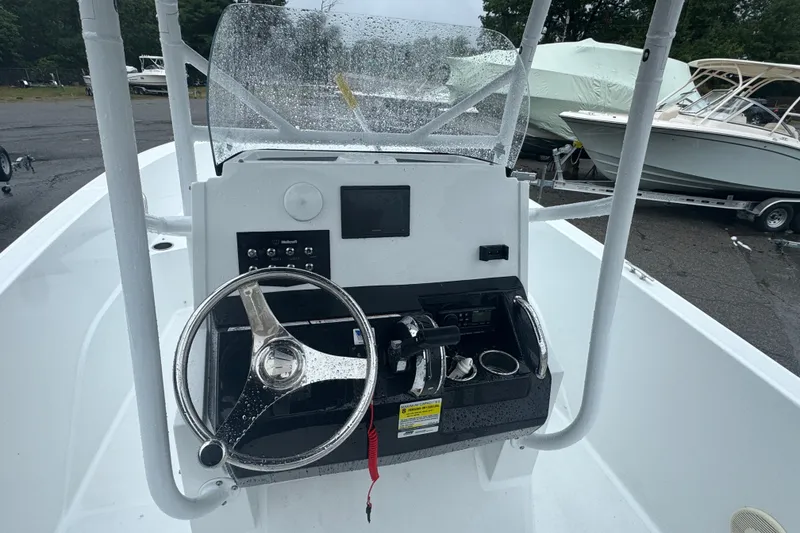 Slide: The Image of 2023 Wellcraft 202 Fisherman boat dashboard with steering wheel and controls in a marina setting. - 5