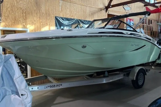The Image of 2026 Hurricane SunDeck Sport 2050 OB boat on trailer in indoor showroom. - 0