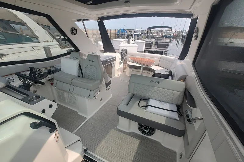 Slide: The Image of 2024 Sea Ray Sundancer 320 Coupe interior with luxurious seating and helm, docked at marina. - 22