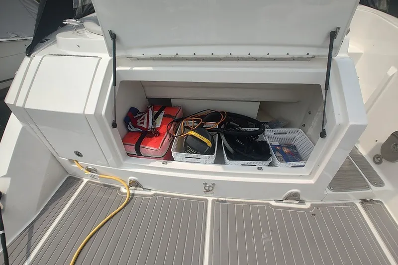 Slide: The Image of Storage compartment of 2024 Sea Ray Sundancer 320 Coupe with safety gear and accessories. - 14