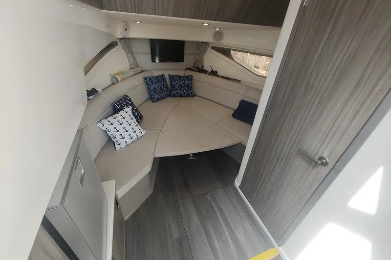 Slide: The Image of 2024 Sea Ray Sundancer 320 Coupe cabin interior with cozy seating and nautical-themed pillows. - 30