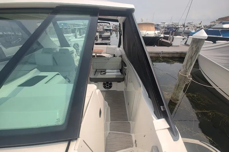 Slide: The Image of 2024 Sea Ray Sundancer 320 Coupe docked, showcasing sleek design and spacious seating area. - 23