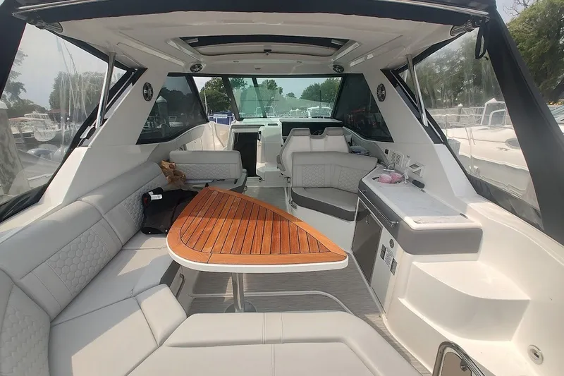 Slide: The Image of 2024 Sea Ray Sundancer 320 Coupe interior with seating and wooden table. - 15