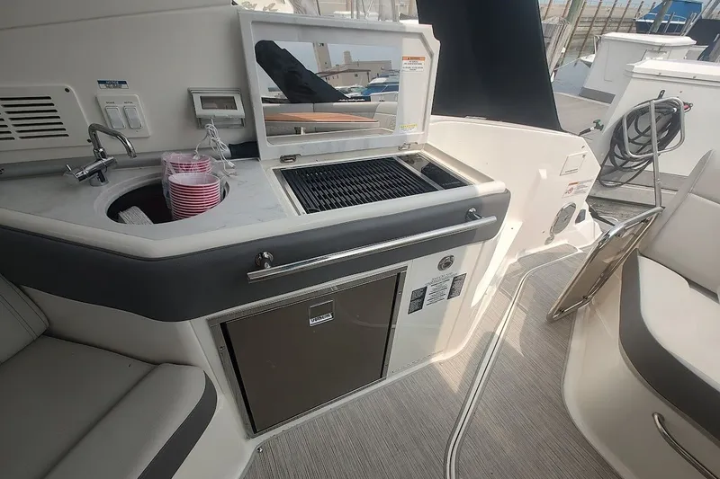 Slide: The Image of 2024 Sea Ray Sundancer 320 Coupe boat interior with sink, grill, and seating area. - 17