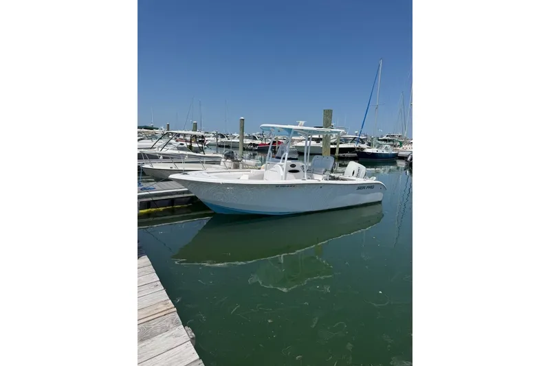 The Image of 2023 Sea Pro 219 Deep V CC boat docked in a marina under clear blue sky. - 1