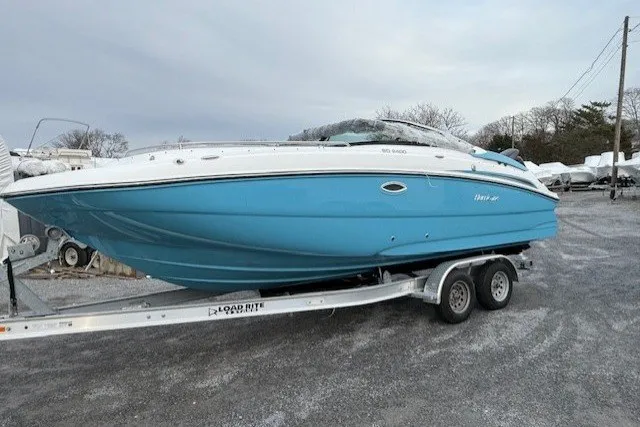 The Image of 2026 Hurricane SunDeck 2400 OB boat on trailer, blue hull, parked outdoors. - 0