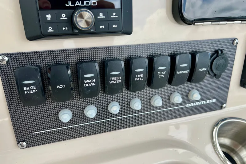 Slide: The Image of Control panel of 2026 Boston Whaler 250 Dauntless boat with various switches and JL Audio system. - 24