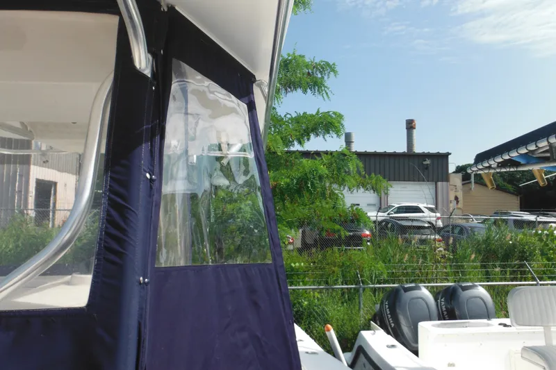 Slide: The Image of 2006 Southport 26 Center Console boat with blue canopy, parked near industrial area. - 75