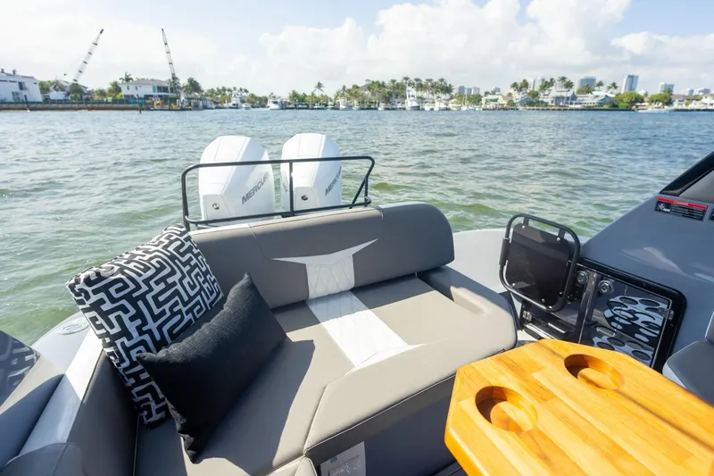 Slide: The Image of 2026 Hanover 305 boat interior with cushions, table, and twin Mercury engines on a sunny day. - 21