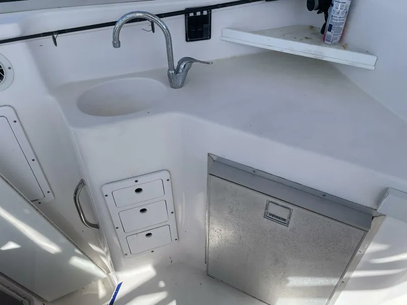 Slide: The Image of The galley of a boat with a sink, faucet, and refrigerator. White cabinets and counter space are visible. - 22