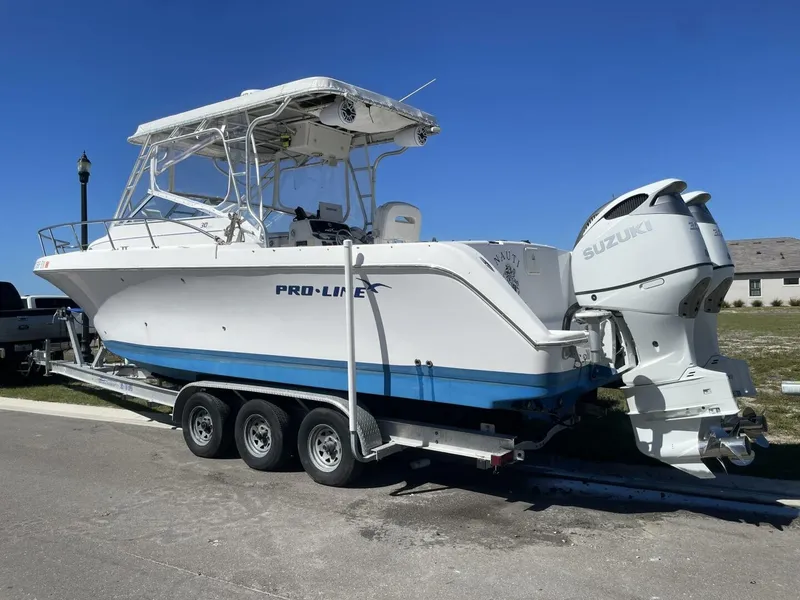 Slide: The Image of A 2004 Pro-Line 30 Express Walkaround on a trailer with twin Suzuki outboard engines. - 30