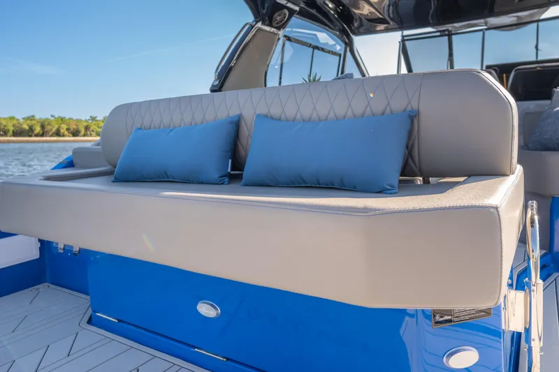 Slide: The Image of Luxurious seating on 2026 Hanover 347 boat with blue cushions, docked by the water. - 12