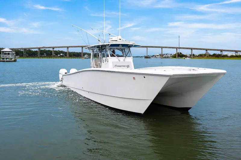 Slide: The Image of 2014 Freeman 37 boat cruising on a calm river with a bridge in the background. - 4
