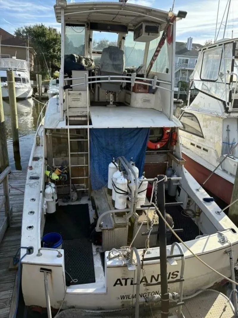Slide: The Image of A 1968 Hatteras 41 Twin Cabin docked. The boat features a spacious aft deck and ladder to the upper helm. - 1