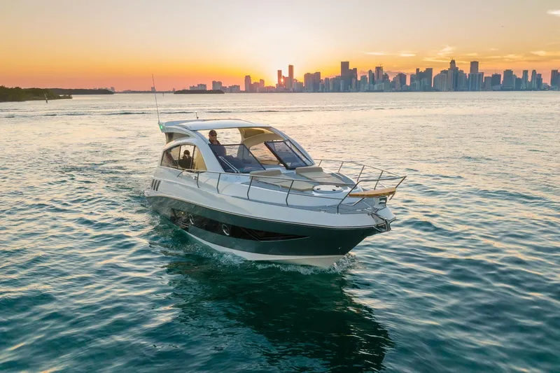 Slide: The Image of 2026 Hanover 375 yacht cruising at sunset with city skyline in background. - 7