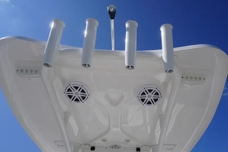 Slide: The Image of Tidewater 220 CC Adventure 2023 boat top view with rod holders and speakers against blue sky. - 30