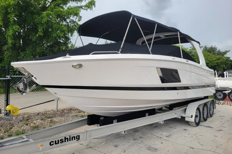 Slide: The Image of 2019 Four Winns H290 OB boat on trailer with black canopy, parked outdoors. - 32